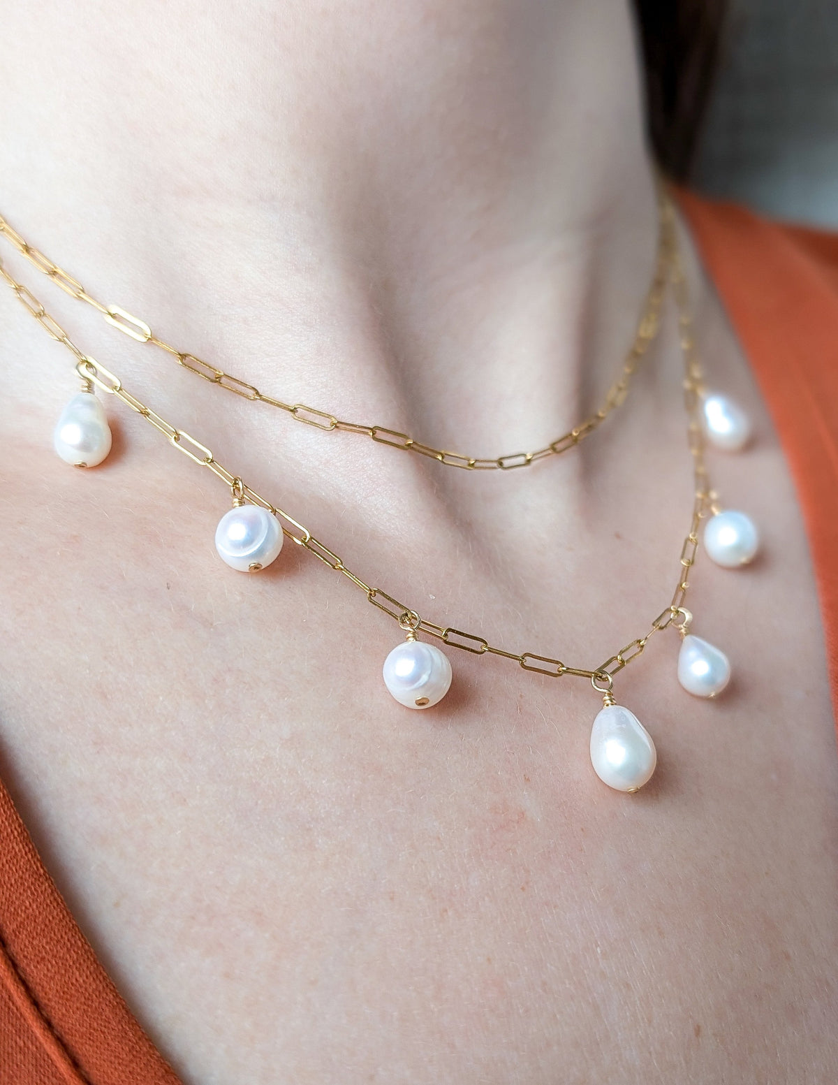Collier Cascade à perles d’eau douce porté en superposition avec une chaîne paperclip dorée.