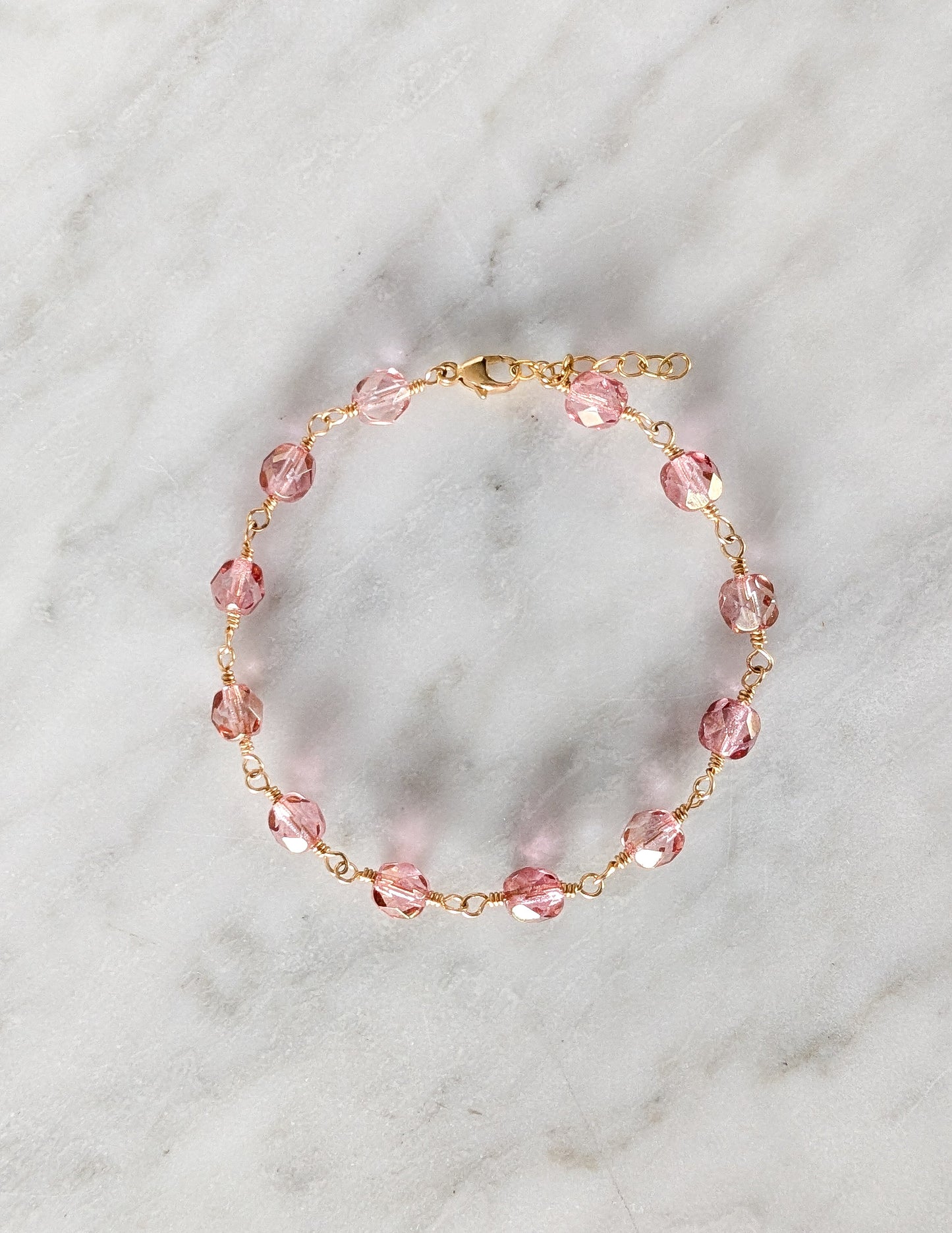 Bracelet Rosalia présenté en cercle, avec perles de verre tchèque roses et finitions en gold filled 14k.