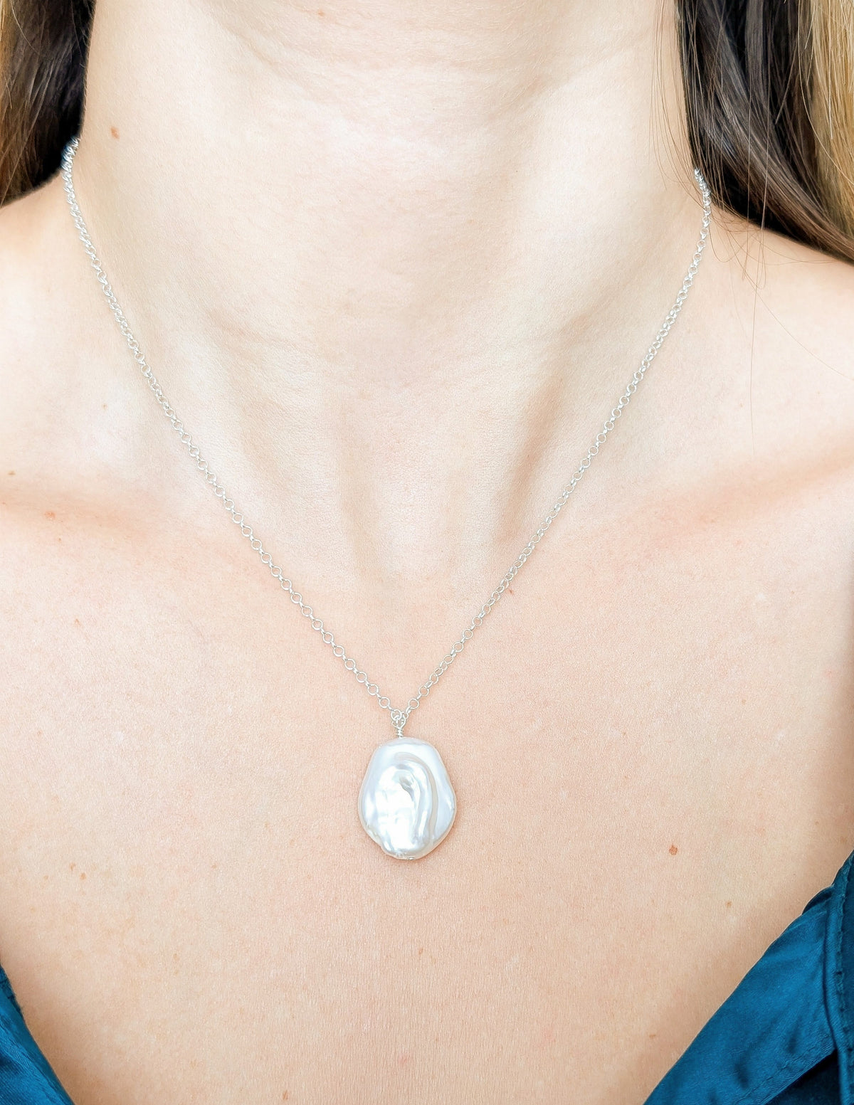 Collier Baroque en argent sterling 925 et perle d’eau douce, porté au cou avec un haut bleu.