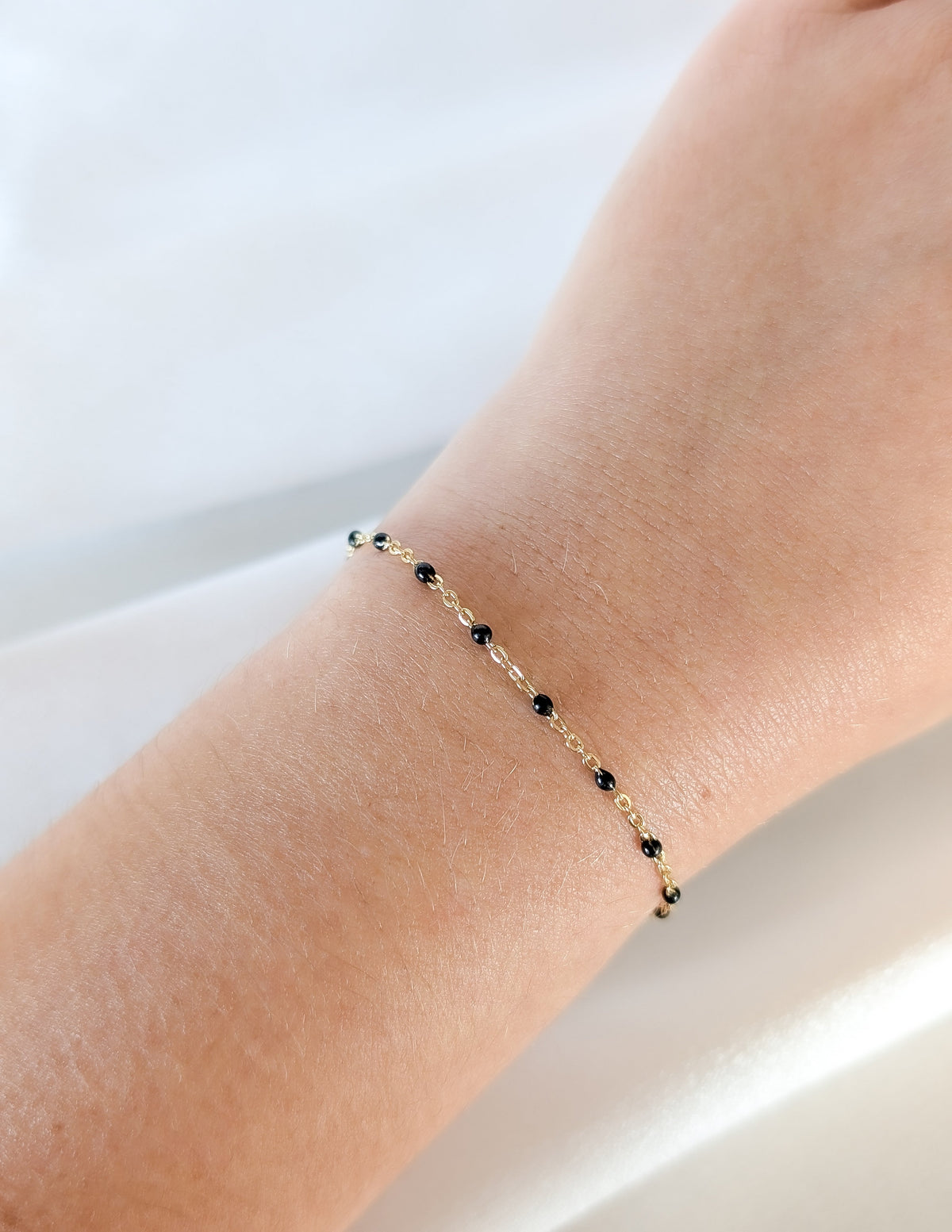 Bracelet Éclipse en gold filled 14k avec petites perles d’émail noir porté au poignet