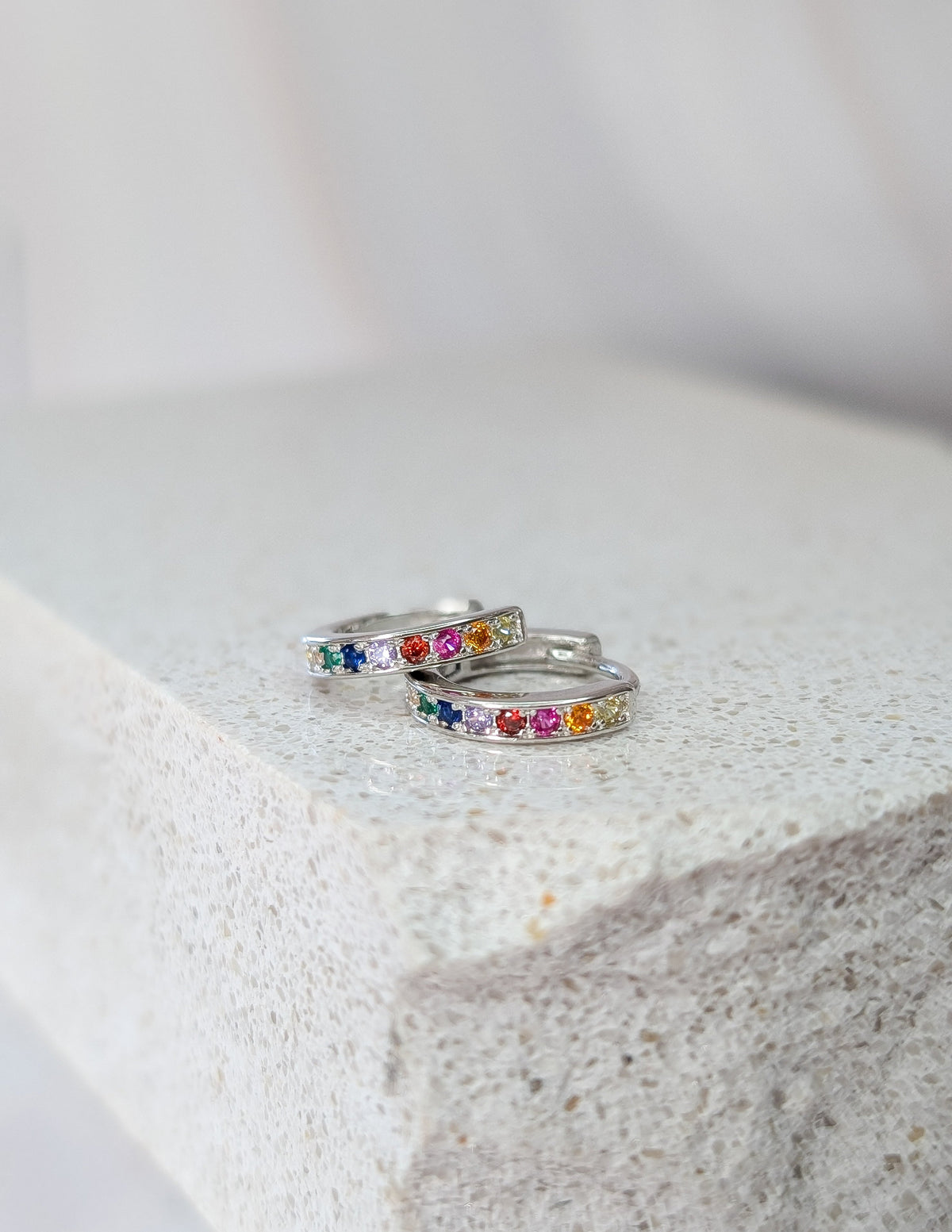 Paire d’anneaux Viva en argent sterling 925, posée à plat pour montrer les zircons multicolores.
