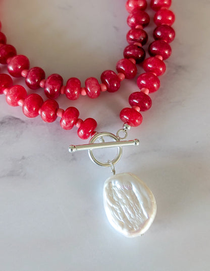 Détail du collier Rubis : perles de verre rouges, fermoir à bascule argenté et perle d’eau douce baroque.
