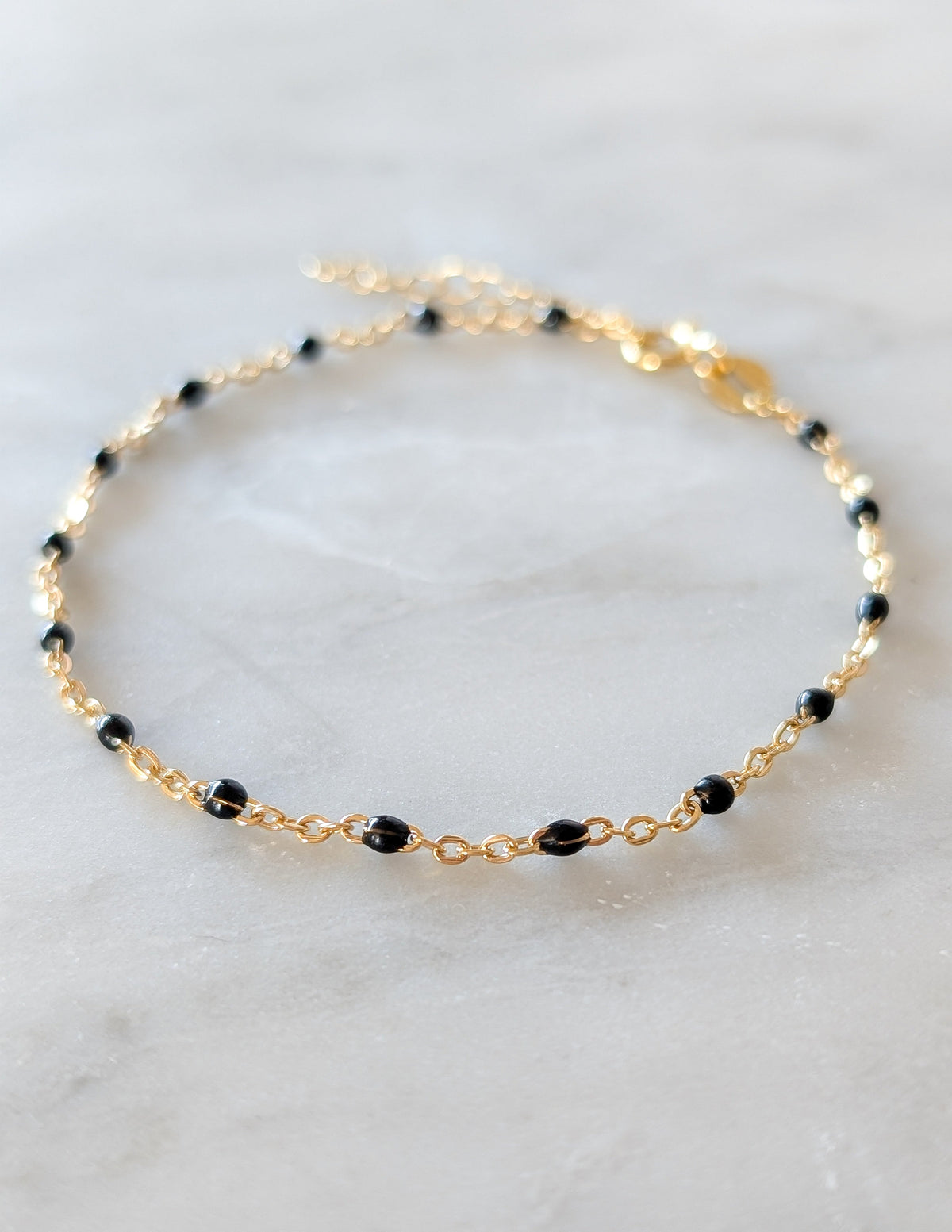Bracelet Éclipse en gold filled 14k et perles d’émail noir présenté à plat