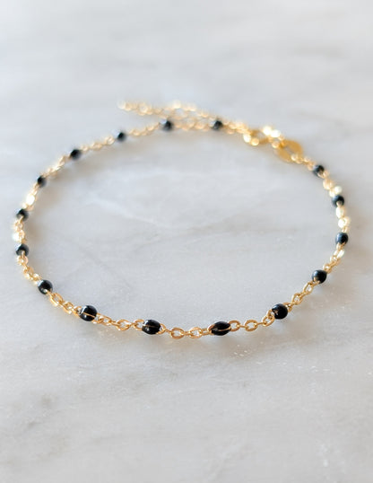 Bracelet Éclipse en gold filled 14k et perles d’émail noir présenté à plat